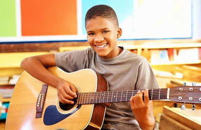 child withh a smile holding a guitar